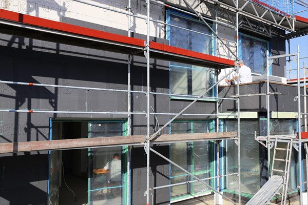 Construction workers insulate a house facade