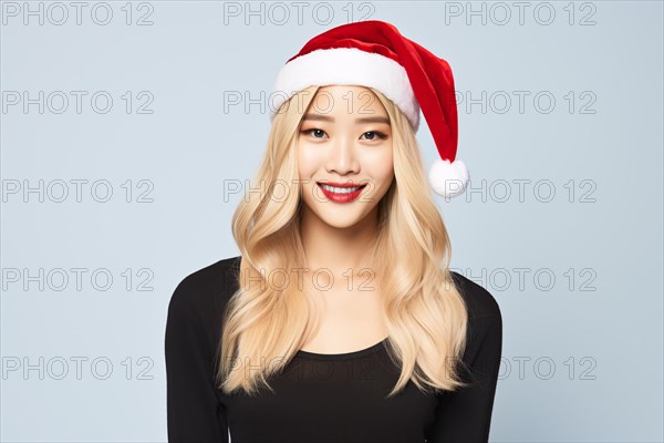 Young Asian woman with long blond hair and red Christmas Santa hat. KI generiert, generiert AI generated