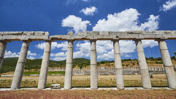Partially reconstructed ancient row of columns in front of an ancient stadium, under a blue sky, Archaeological site, Ancient Messene, capital of Messinia, Messini, Peloponnese, Greece, Europe