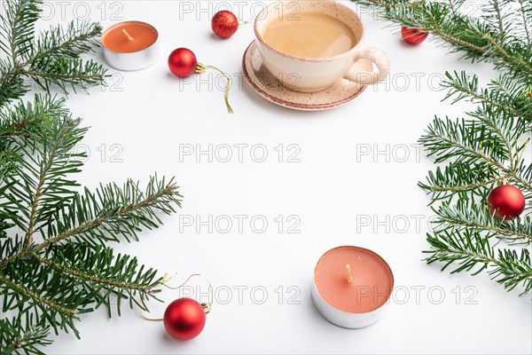 Christmas or New Year frame composition. Decorations, red balls, fir and spruce branches, cup of coffee, candles on a white paper background. Side view, copy space