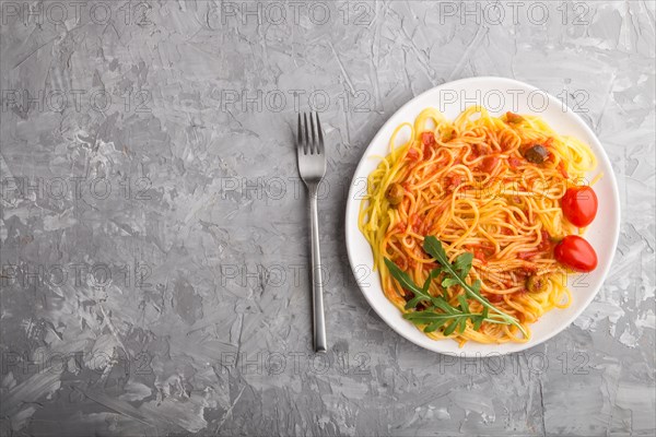 Corn noodles with tomato sauce and arugula on a gray concrete background. Top view, flat lay, copy space