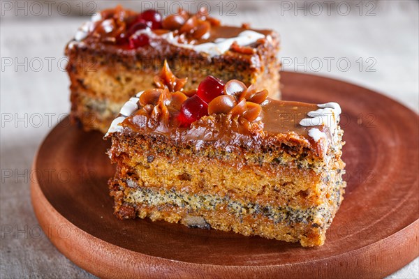A piece of cake with caramel cream and poppy seeds on a wooden kitchen board. close up, selective focus, white background