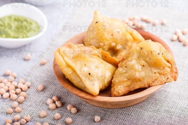 Traditional indian food samosa in wooden plate with mint chutney on a gray concrete background. side view, close up