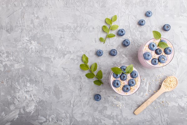 Yoghurt with blueberry and sesame in a glass and wooden spoon on gray concrete background. top view, flat lay, copy space