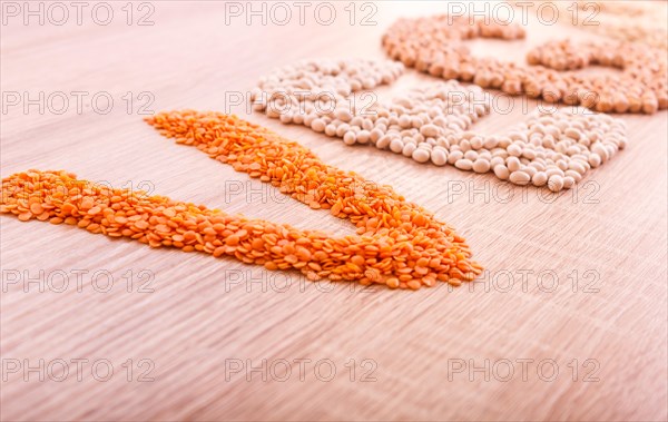 Word Vegan made of lentils, buckwheat, beans, rice and chickpeas on a wooden background