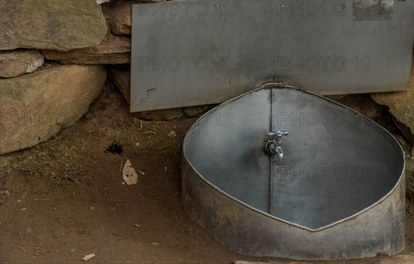 Public water faucet with metal basin located in mountain park for use by hikers visiting the area in South Korea