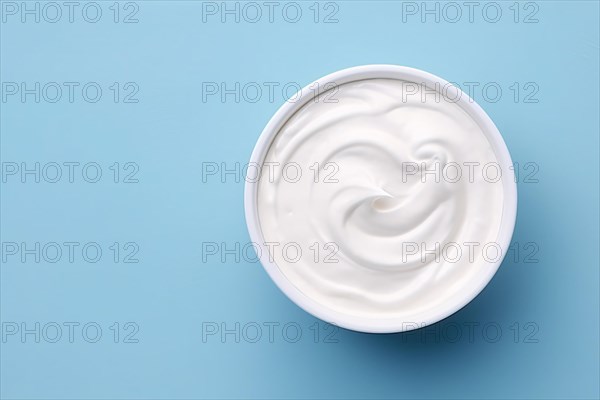 Top view of bowl with white quark or cream on side of blue background with copy space. KI generiert, generiert AI generated