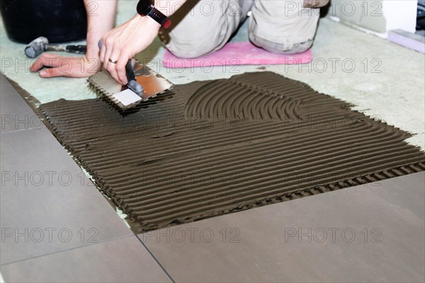 Tiler lays modern large floor tiles in a bathroom