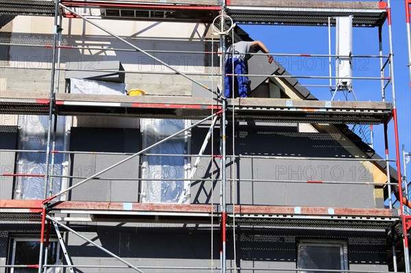 Construction workers insulate a house facade