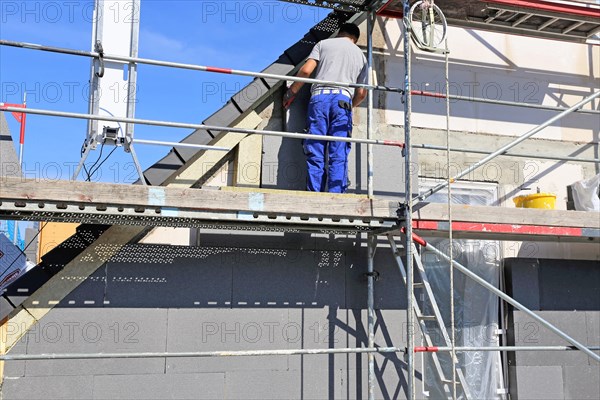 Construction workers insulate a house facade