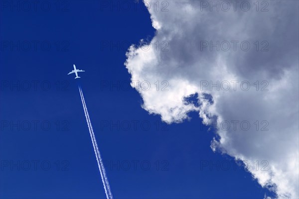 A passenger plane with vapour trails high in the blue sky