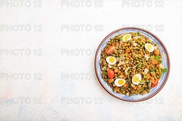 Mung bean porridge with quail eggs, tomatoes and microgreen sprouts on a white concrete background. Top view, flat lay, copy space