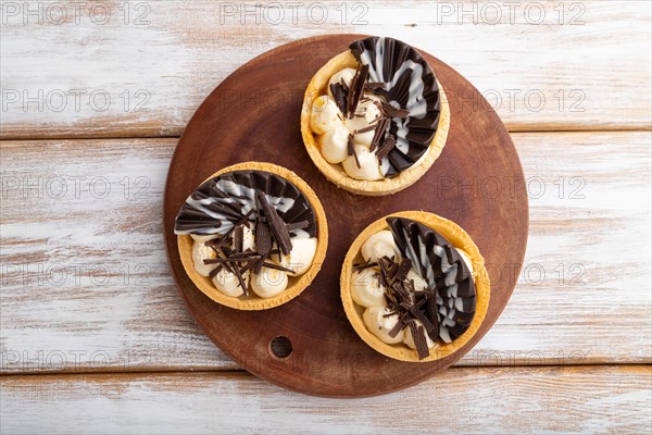 Sweet tartlets with chocolate and cheese cream on a white wooden background. top view, flat lay, copy space.close up