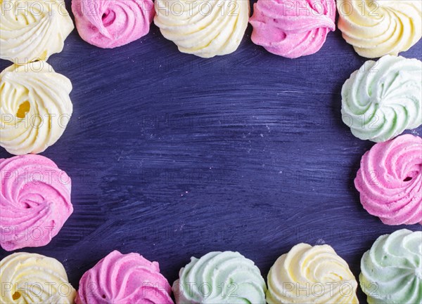 Colorful frame of multicolored meringues on black wooden background. copy space, top view, flat lay