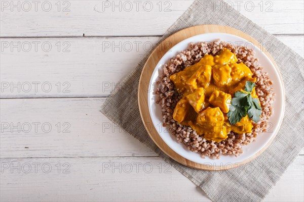Buckwheat with chicken curry sauce with cashew on white wooden background. top view, copy space