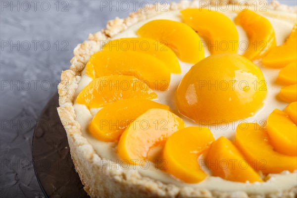 Round peach cheesecake on a gray concrete background. side view, close up