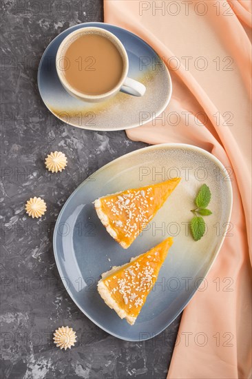Two pieces of traditional american pumpkin pie with cup of coffee on a black concrete background and orange textile. top view, flat lay, close up, contrast