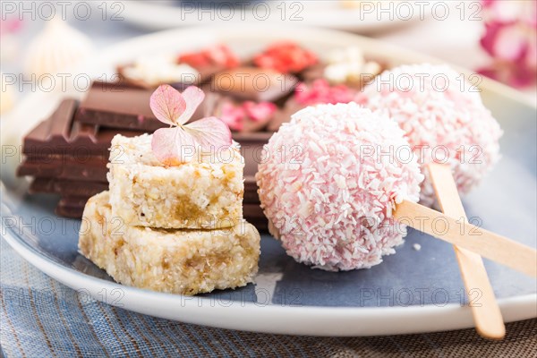 A pieces of homemade chocolate with coconut candies on a blue and brown textile. side view, close up, selective focus