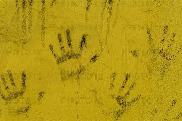 Black hand prints on side of cracked yellow wall in South Korea