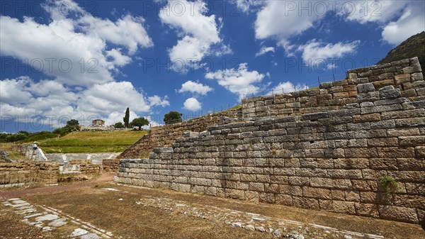 Historic remains of ancient walls against a cloudy sky and green landscape, Ancient city wall, Archaeological site, Ancient Messene, Capital of Messinia, Messini, Peloponnese, Greece, Europe