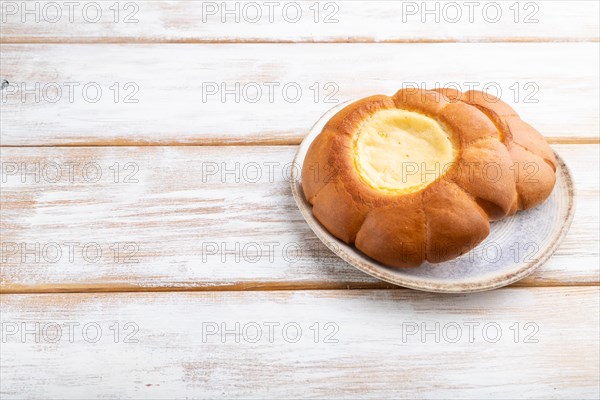 Sour cream bun on a white wooden background. Side view, copy space