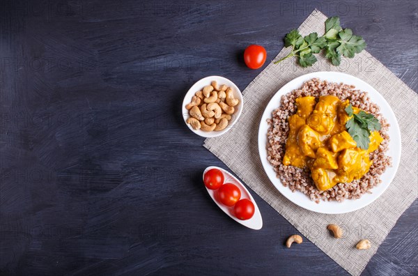 Buckwheat with chicken curry sauce with cashew on black wooden background. top view, copy space