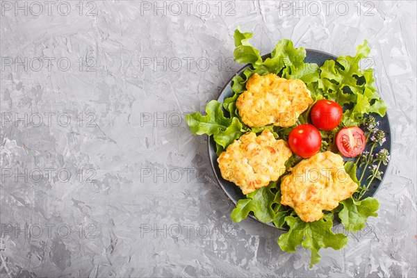 Minced chicken cutlets with lettuce, tomatoes and herbs on a gray concrete background. top view, flat lay, copy space