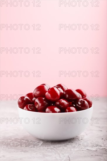 Fresh red sweet cherry in white bowl on gray and pink background. side view, close up, selective focus, copy space
