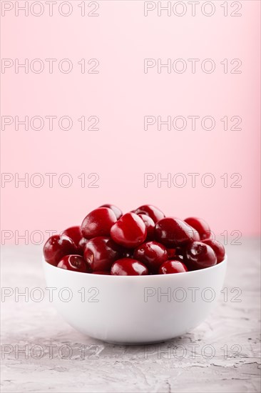 Fresh red sweet cherry in white bowl on gray and pink background. side view, close up, selective focus, copy space