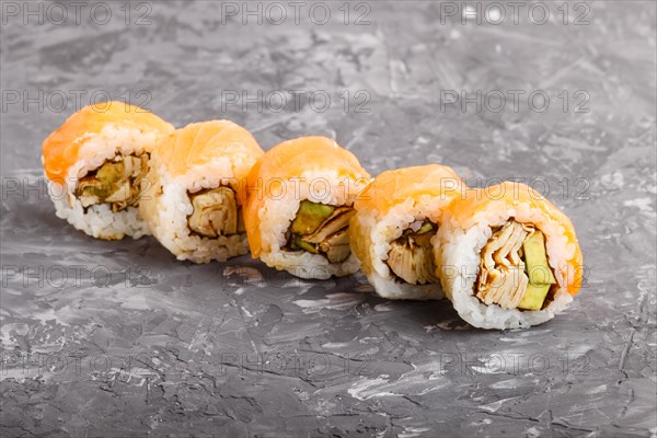 Japanese maki sushi rolls with salmon, avocado and omelette on black concrete background. Side view, close up, copy space