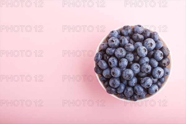 Fresh blueberry in white bowl on pink background. top view, copy space, flat lay