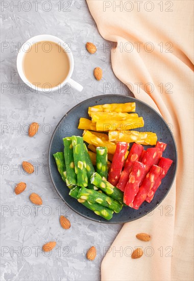 Set of various traditional turkish delight (rahat lokum) in blue ceramic plate with cup of coffee on a gray concrete background. top view, flat lay