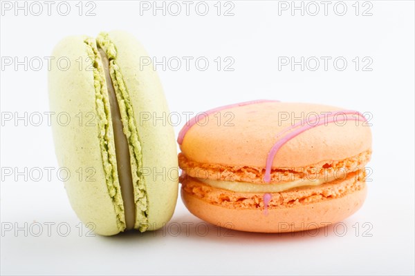 Orange and green macarons or macaroons cakes isolated on white background. side view, close up, macro