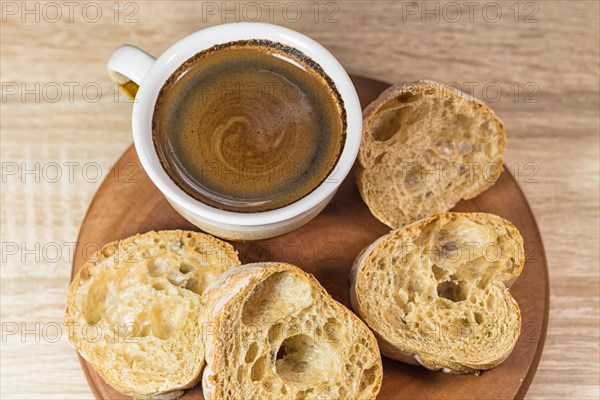 Sliced bread and a cup of coffee on a wooden board and linen tablecloth