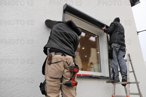 Craftsmen install a front-mounted roller shutter