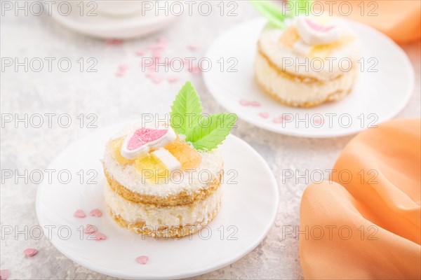 Decorated cake with milk and coconut cream with cup of coffee on a gray concrete background and orange textile. Side view, close up, selective focus