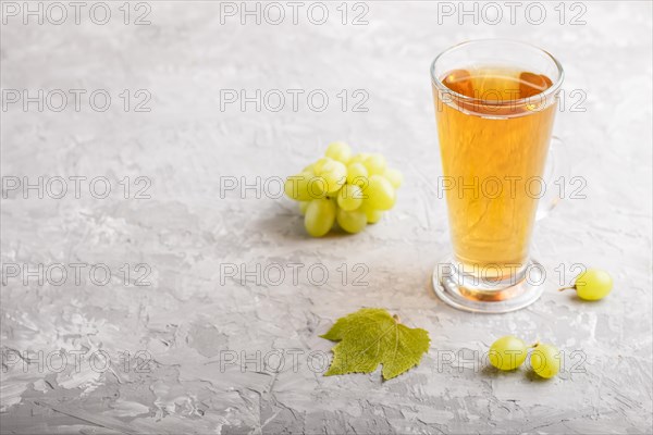 Glass of green grape juice on a gray concrete background. Morninig, spring, healthy drink concept. Side view, copy space
