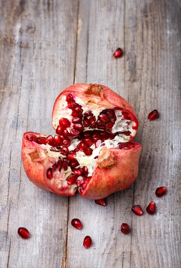 Opened ripe garnet with seeds on a rustic wooden background