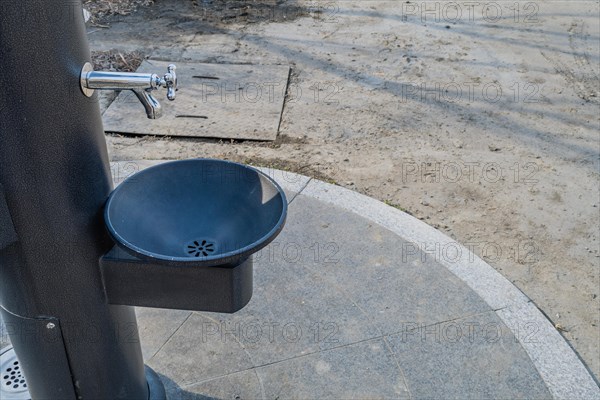 Black metal water drinking fountains near walkway in a public park in South Korea