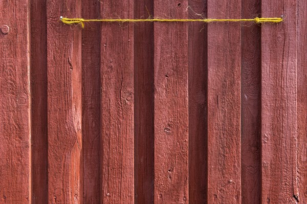 Red wooden wall of a fisherman's hut with yellow string, Hvide Sande, Midtjylland region, Denmark, Europe