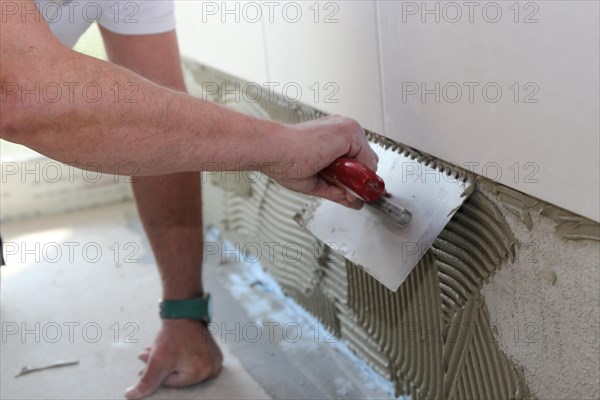 Tiler lays tiles on the wall