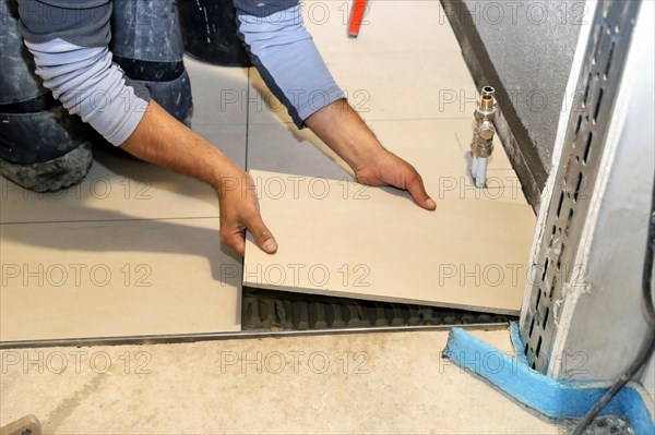 Tiler lays modern large floor tiles in a bathroom