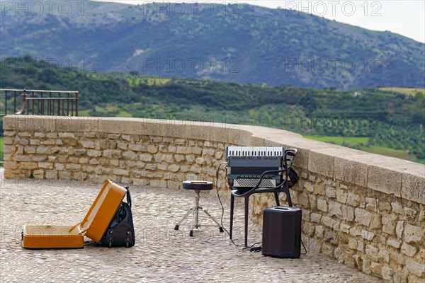 A street musician playing the accordion with a mountainous landscape in the background