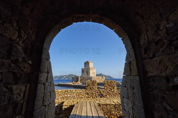 View through an arched entrance to a castle by the sea, octagonal medieval tower. Islet of Bourtzi, sea fortress of Methoni, Peloponnese, Greece, Europe