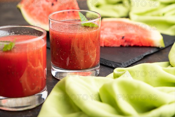 Watermelon juice with chia seeds and mint in glass on a black concrete background with green textile. Healthy drink concept. Side view, close up, selective focus