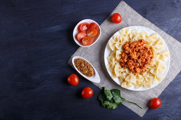 Farfalle bolognese pasta with minced meat on black wooden background. top view, copy space