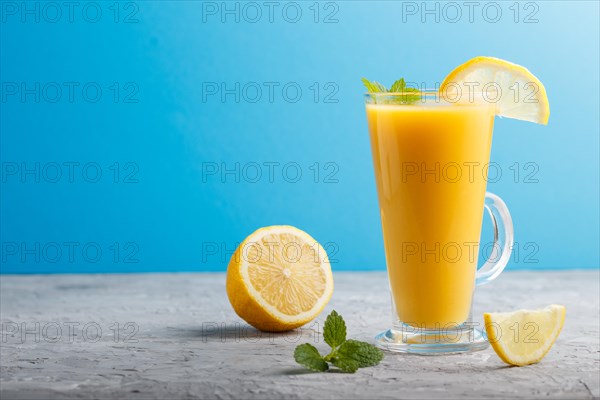 Glass of lemon drink on a gray and blue background. Morninig, spring, healthy drink concept. Side view, copy space