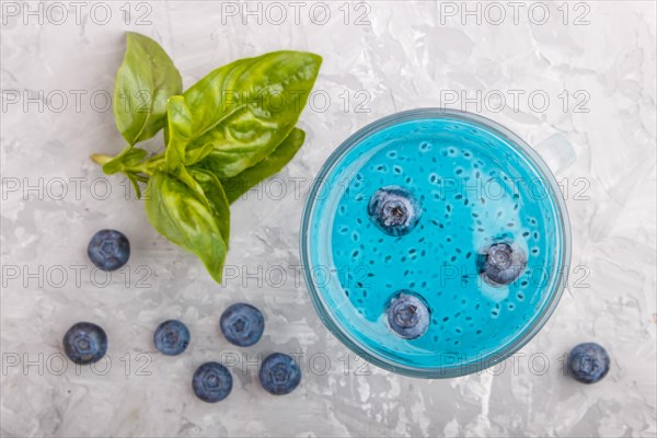 Glass of blueberry blue colored drink with basil seeds on a gray concrete background. Morninig, spring, healthy drink concept. Top view, close up, flat lay