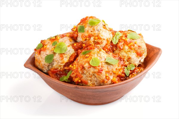Pork meatballs with tomato sauce, oregano leaves, spices and herbs in clay bowl isolated on white background. side view, close up