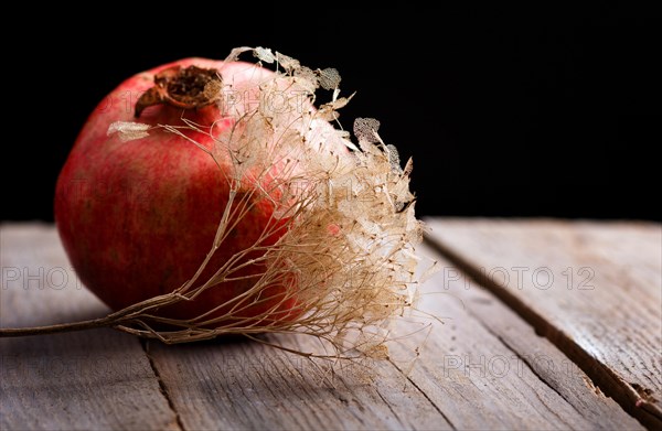 Ripe garnet with a branch on a rustic wooden background